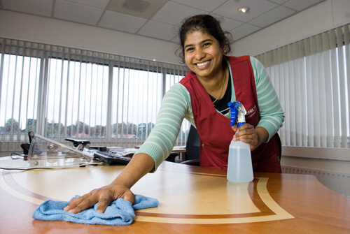 Medewerkster van Schilten maakt het bureau met een glimlach schoon